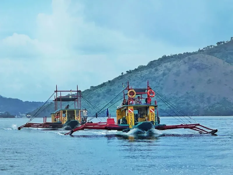 Deux bateaux de pêche traditionnels naviguent sur une mer calme