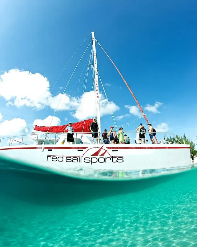 Catamaran blanc avec des personnes à bord, vue moitié aérienne moitié sous-marine