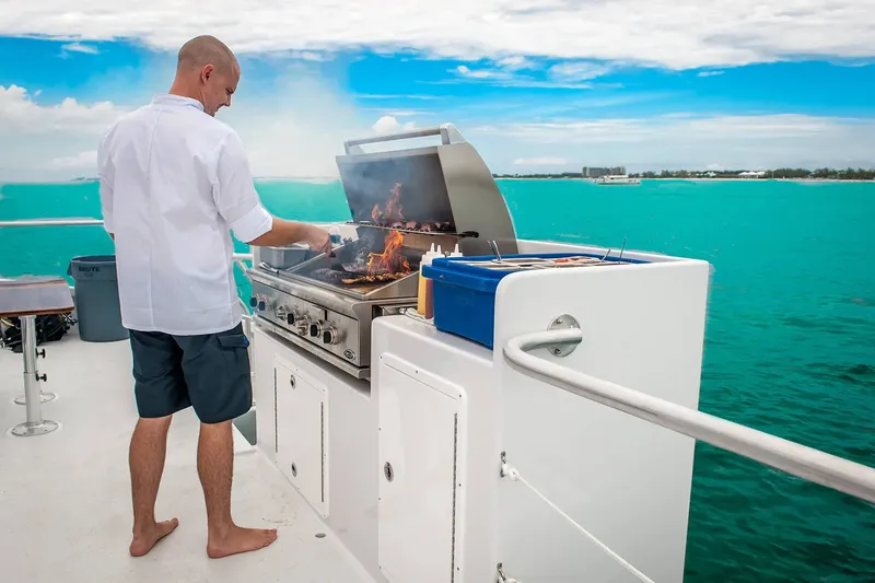 Un homme cuisine sur un barbecue installé sur le pont d'un bateau