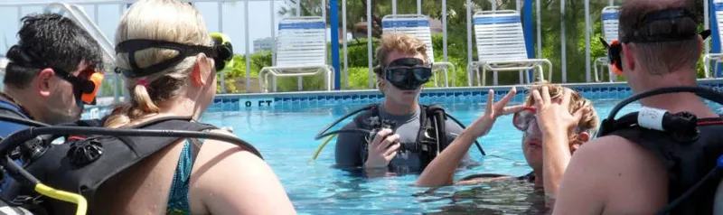 Quatre plongeurs en formation dans une piscine avec leur équipement