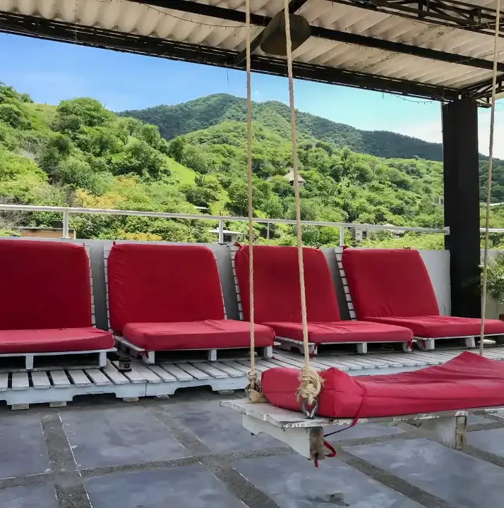 Terrasse avec des assises rouges, vue sur une colline verdoyante