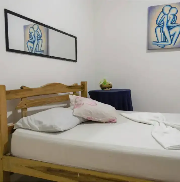 Chambre simple avec lit fait, deux tableaux abstraits aux murs