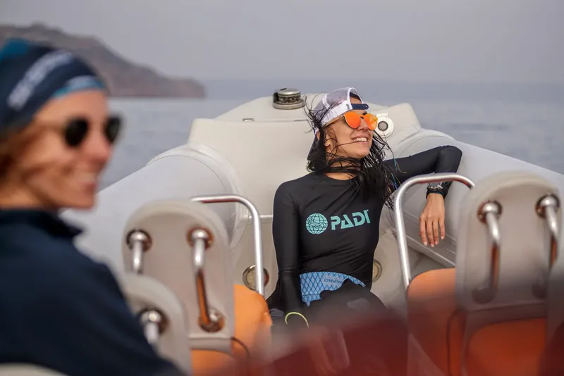 Deux plongeuses souriantes se reposent sur un bateau pneumatique en mer