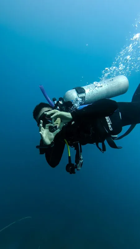 Plongeur en combinaison noire avec bouteille et détendeur sous l'eau