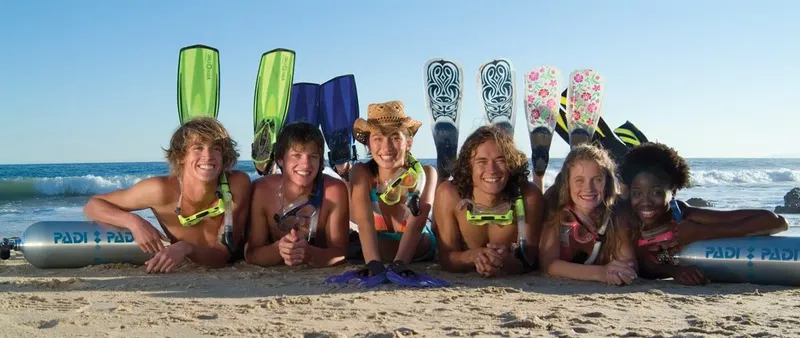 Groupe de jeunes adultes souriants avec équipement de plongée sur plage