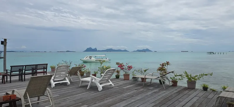 Terrasse en bois avec transats, mer turquoise et îles au loin