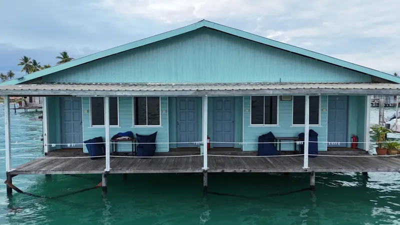 Bâtiment turquoise sur pilotis au-dessus d'une eau turquoise calme