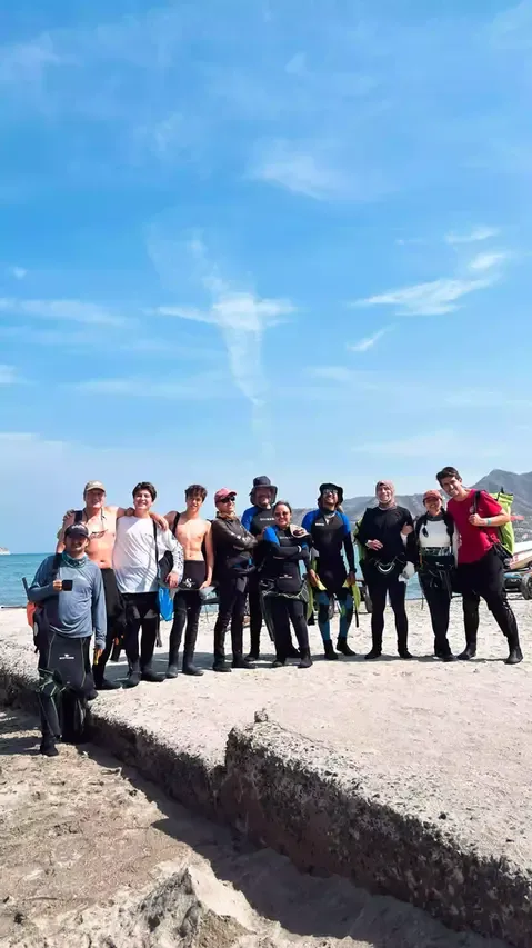 Groupe de personnes souriantes en combinaison de plongée sur un quai