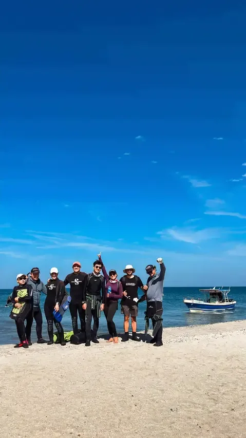Groupe de personnes en combinaisons de plongée sur une plage ensoleillée