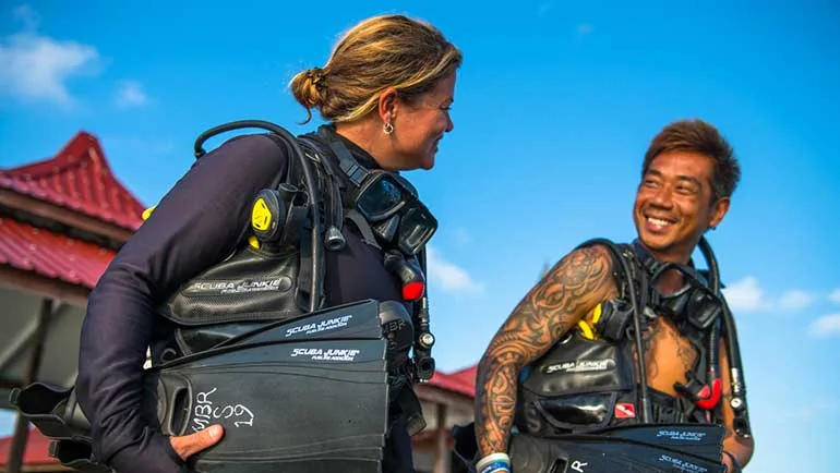 Deux plongeurs souriants équipés prêts pour une sortie en mer