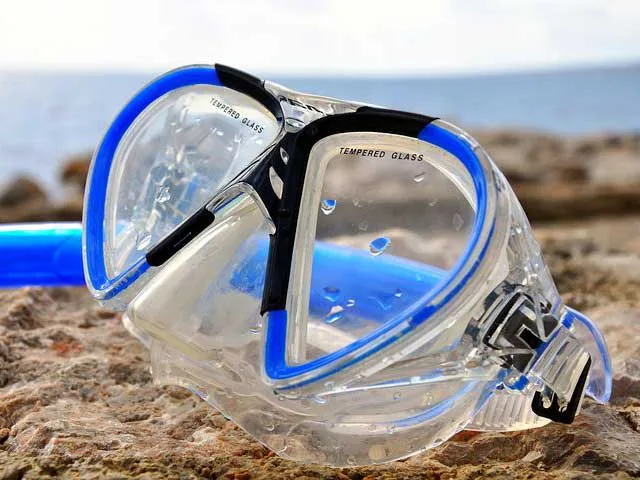 Masque de plongée bleu et noir sur des rochers au soleil