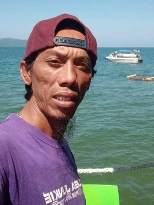 Portrait d'un homme souriant avec un bateau en arrière-plan