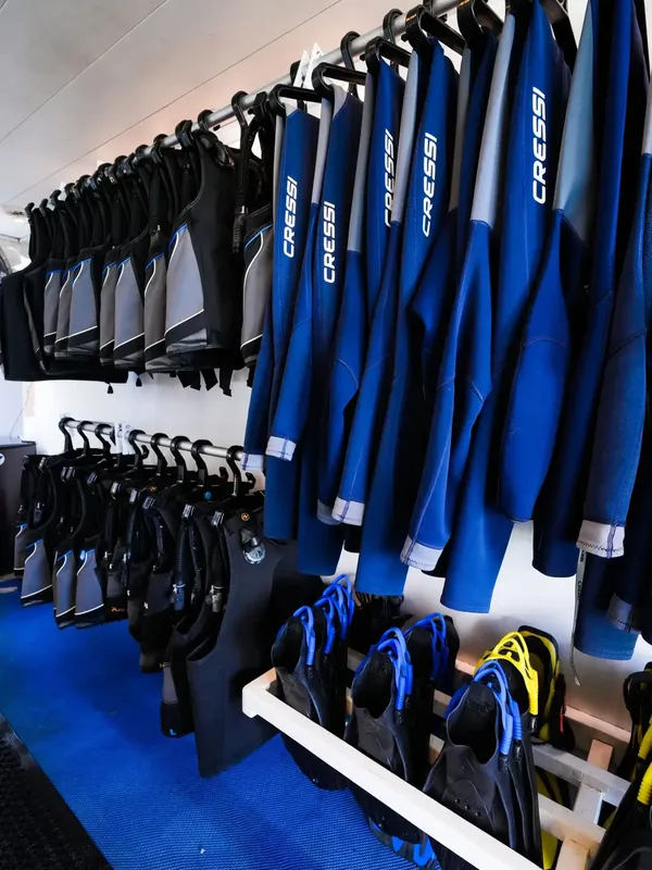 Rangées de combinaisons de plongée Cressi bleues et noires suspendues au centre