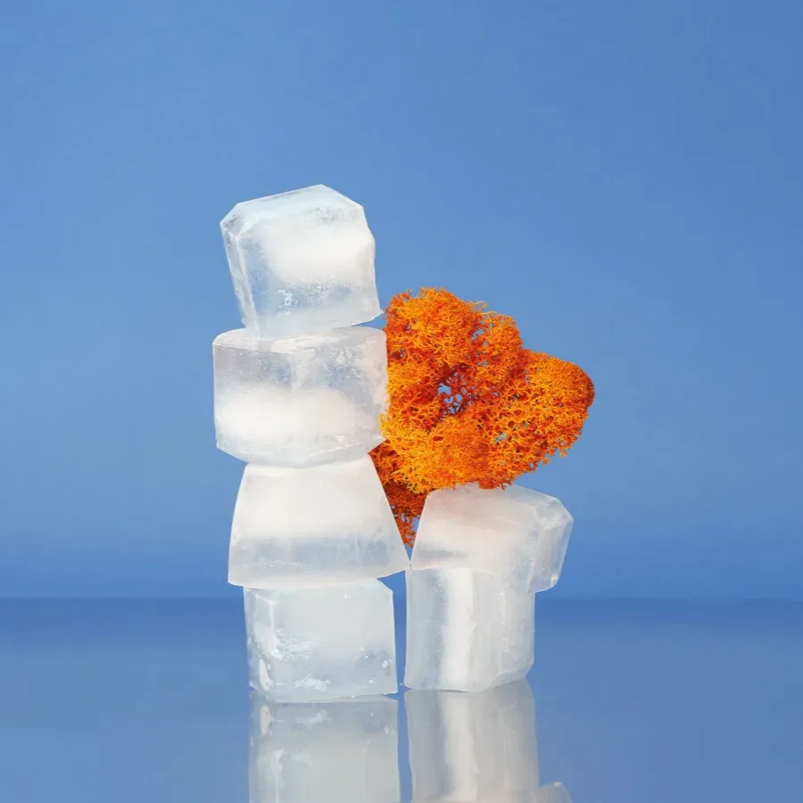 Éponge orange posée sur une pile de cubes de glace transparents