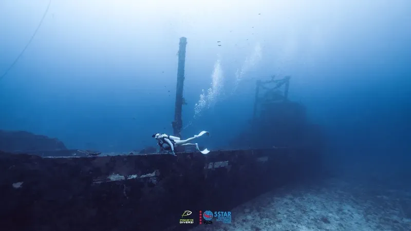 Plongeuse explorant une épave sous-marine, bulles et structure métallique