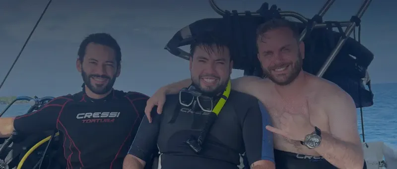 Trois plongeurs souriants posent sur un bateau après une immersion