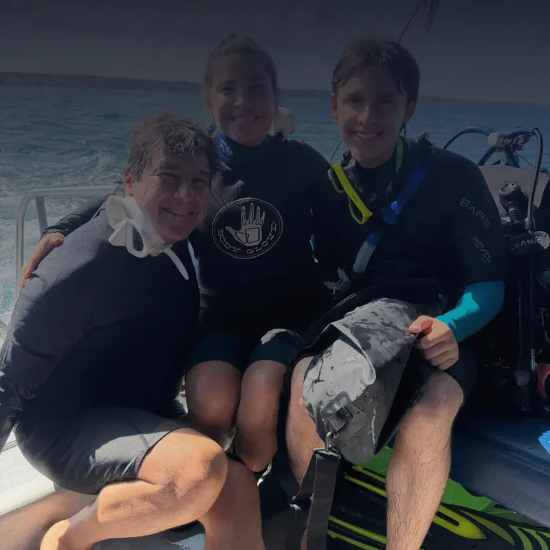 Deux plongeurs souriants sur un bateau, équipés et prêts à plonger