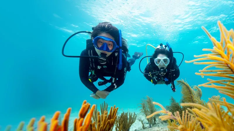 Deux plongeurs sourient face à la caméra dans l'eau turquoise
