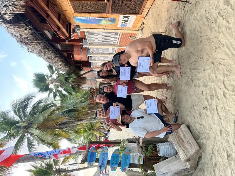 Groupe de plongeurs souriants tenant leurs certificats sur une plage