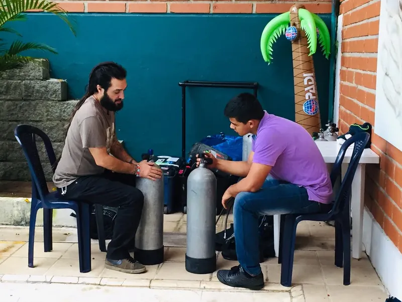 Deux plongeurs assis vérifient leur équipement près des bouteilles