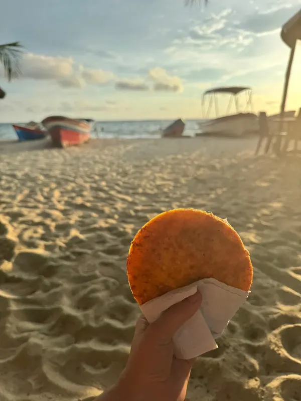 Main tenant une galette de manioc sur une plage ensoleillée