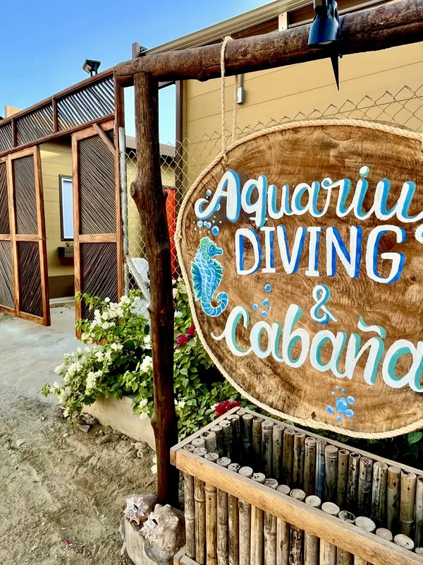 Panneau en bois avec inscription 'Aquarium Diving & cabaña' et fleurs