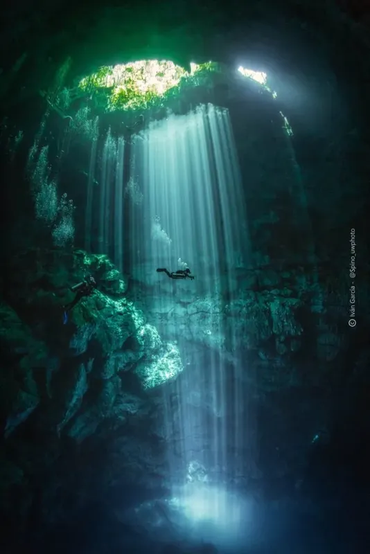 Plongeur explorant une grotte sous-marine éclairée par un rayon de soleil