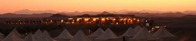 Bâtiments éclairés au coucher du soleil dans un paysage désertique montagneux
