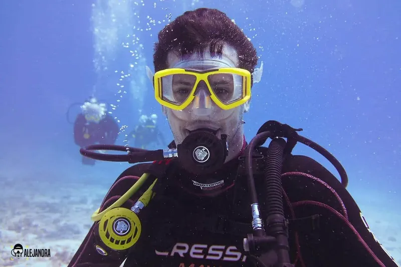 Plongeur avec masque jaune et détendeur, regardant vers la caméra sous l'eau