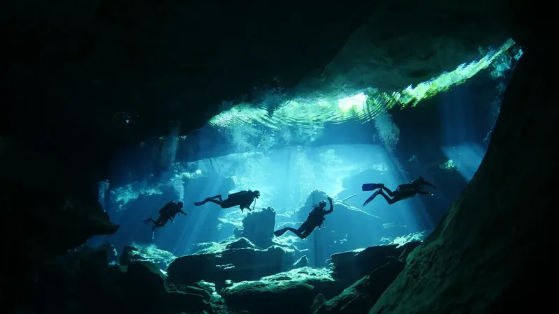 Plongeurs explorant une grotte sous-marine éclairée par des rayons de soleil