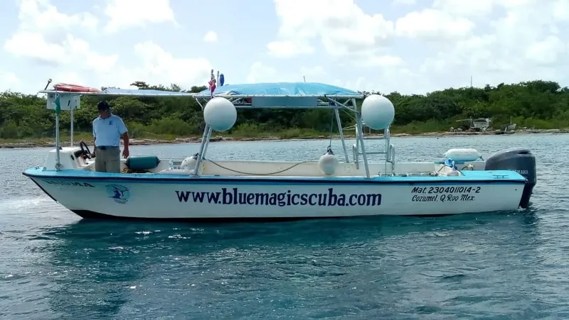 Bateau de plongée blanc avec un homme à bord sur l'eau turquoise