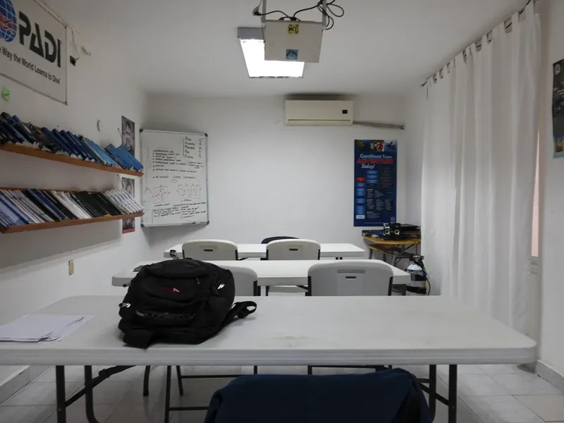 Salle de cours de plongée avec équipement, projecteur et tableau blanc