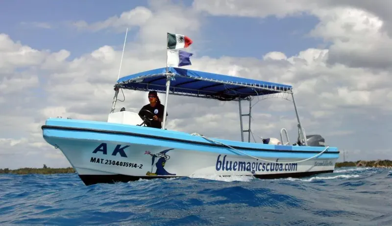 Bateau de plongée bleu en mer avec une personne à bord