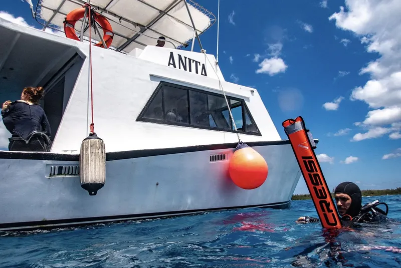 Plongeur près d'un bateau blanc avec une personne à bord