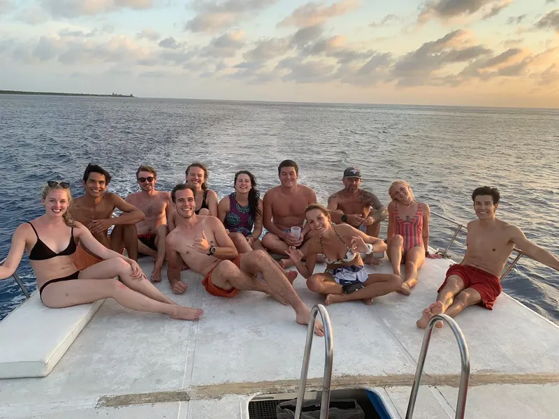 Groupe de personnes souriantes sur un bateau en mer, ciel nuageux