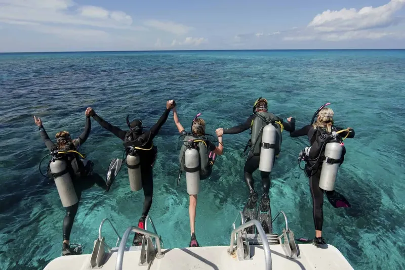 Plongeurs sur le point de sauter d'un bateau en mer turquoise
