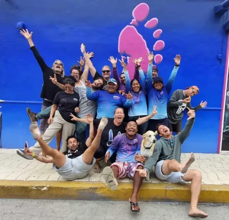 Groupe de personnes souriantes et enthousiastes posant devant un mur bleu