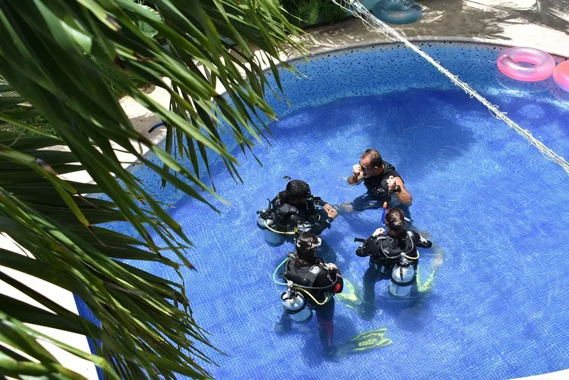 Formation plongée en piscine avec instructeur et trois élèves équipés