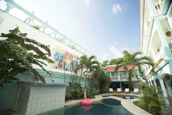 Cour intérieure avec piscine, végétation tropicale et bâtiment turquoise