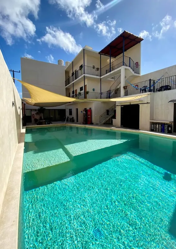 Bâtiment blanc avec piscine turquoise et rangée de bouteilles de plongée