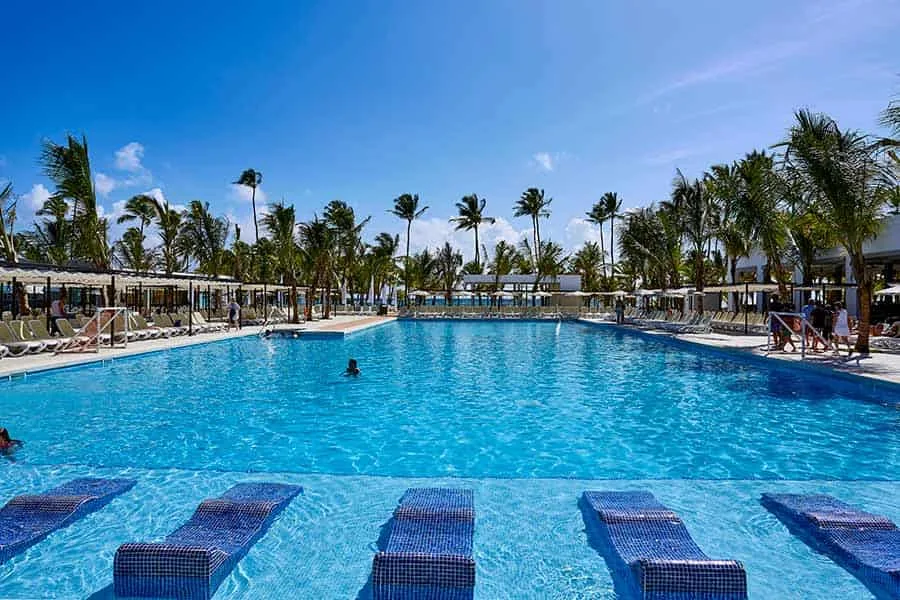 Piscine d'hôtel avec transats, palmiers et quelques baigneurs