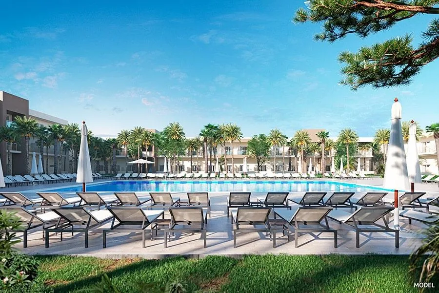 Piscine d'un complexe hôtelier avec transats et palmiers ensoleillés