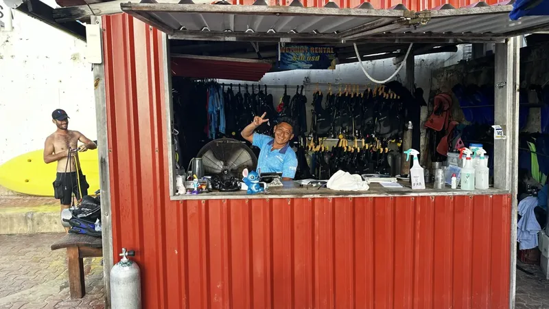 Un homme souriant derrière un comptoir de location de matériel de plongée