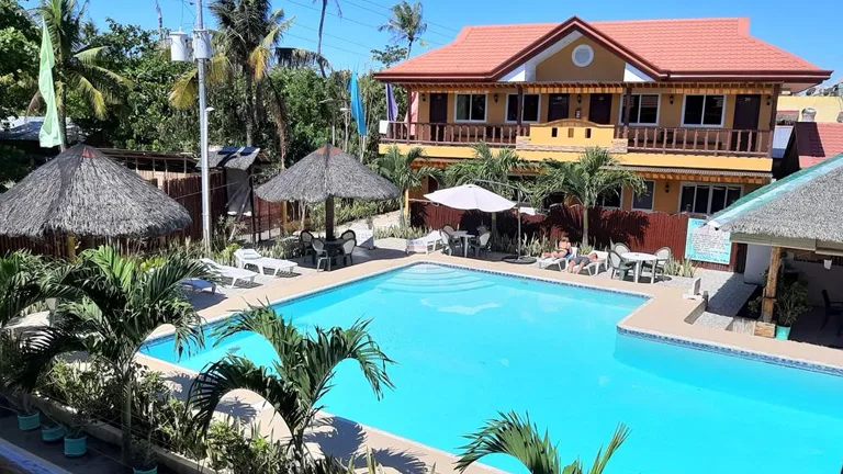 Piscine d'un centre de vacances avec des transats et végétation tropicale