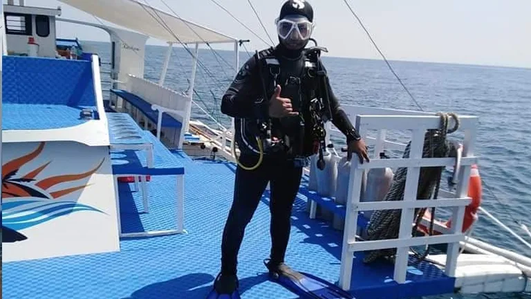 Plongeur en combinaison complète sur le pont d'un bateau bleu