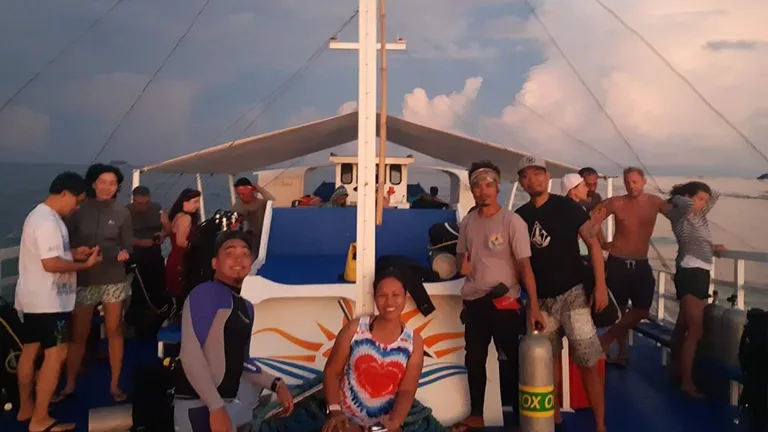 Groupe de plongeurs souriants sur le pont d'un bateau de plongée