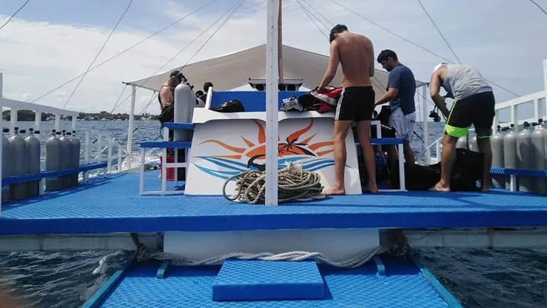 Préparation de matériel de plongée sur le pont d'un bateau bleu