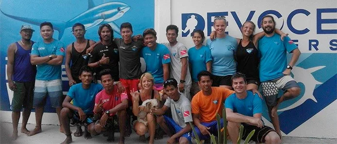 Groupe de personnes souriantes posant devant un mur décoré de requins