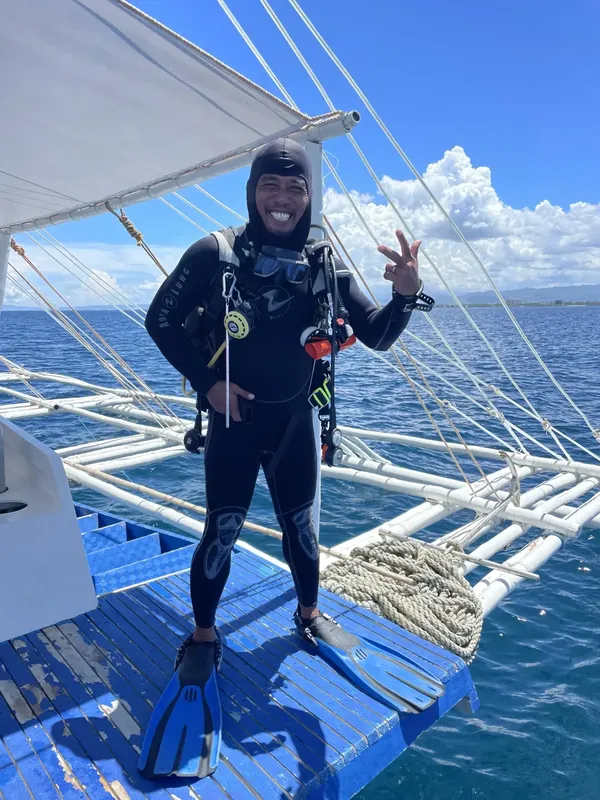 Plongeur souriant en combinaison complète sur le pont d'un bateau
