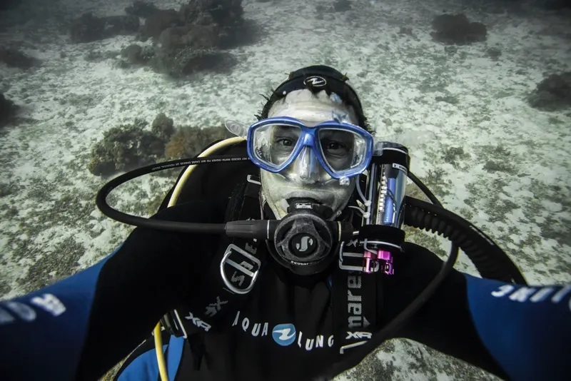 Plongeur souriant avec masque et détendeur, prise de vue sous-marine